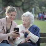 A woman showing the recallify productivity app on her smartphone to another woman