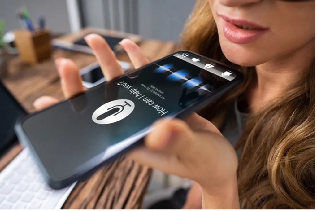 Woman speaking into a smartphone to capture a voice note, showing how AI memory apps use real time transcription to record and organise everyday information