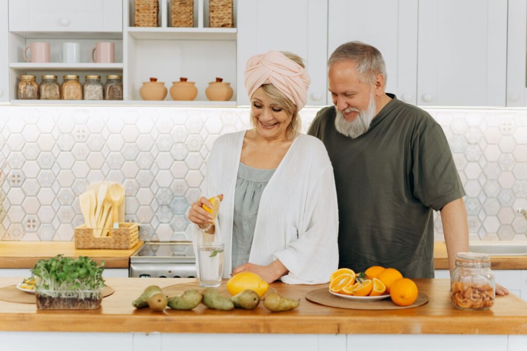An older couple preparing food together in a bright kitchen