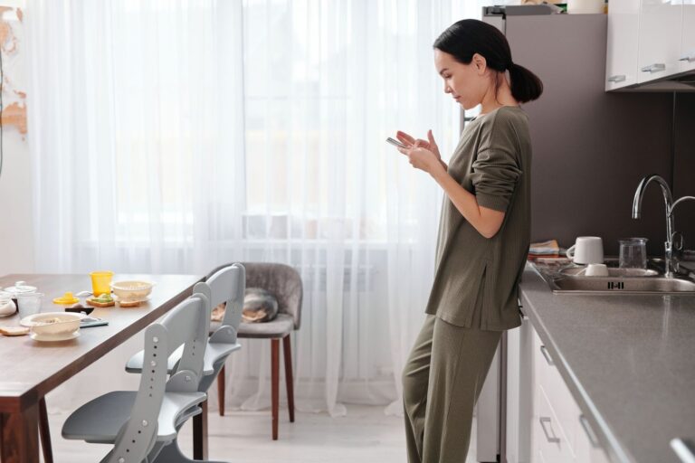 Woman at home in a bright kitchen, checking her phone