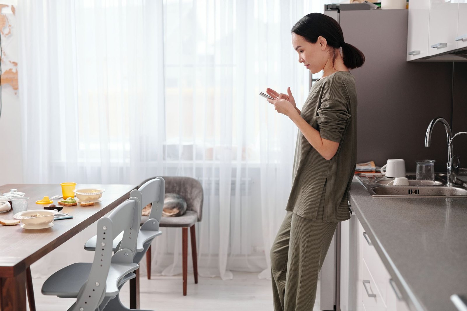 Woman at home in a bright kitchen, checking her phone