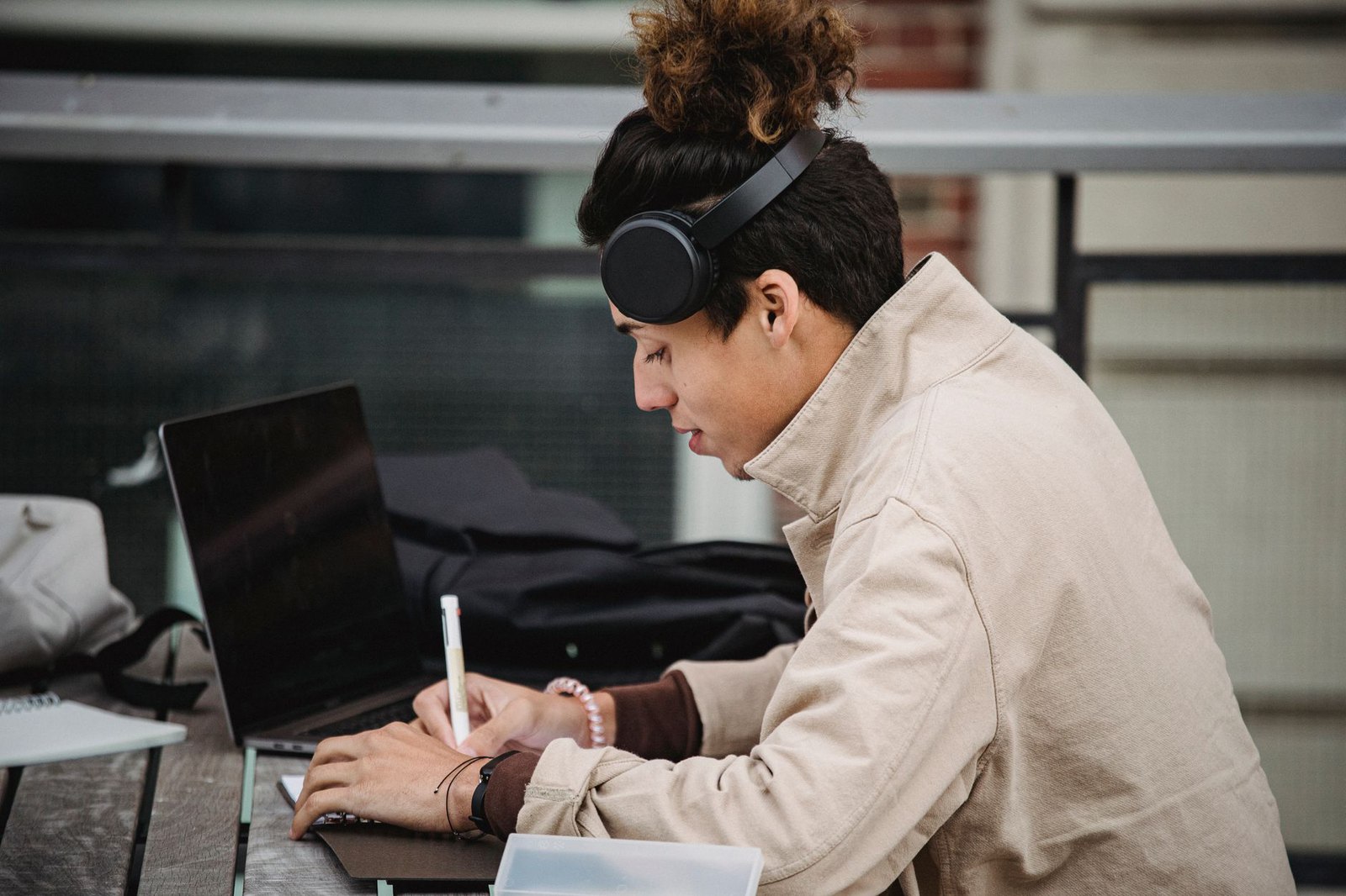 DSA software for memory difficulties, a university student with headphones taking notes beside a laptop